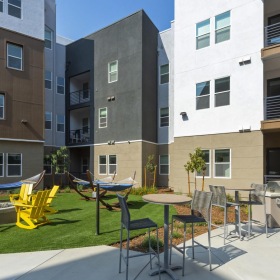 Everything within reach a patio with tables and chairs and buildings in the background